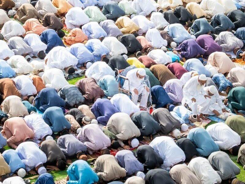 crowd of praying muslims kneeling and bowing